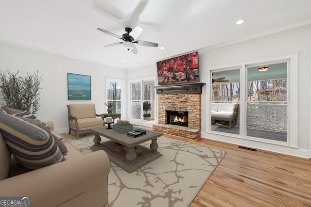 living room with ornamental molding, wood finished floors, visible vents, and ceiling fan