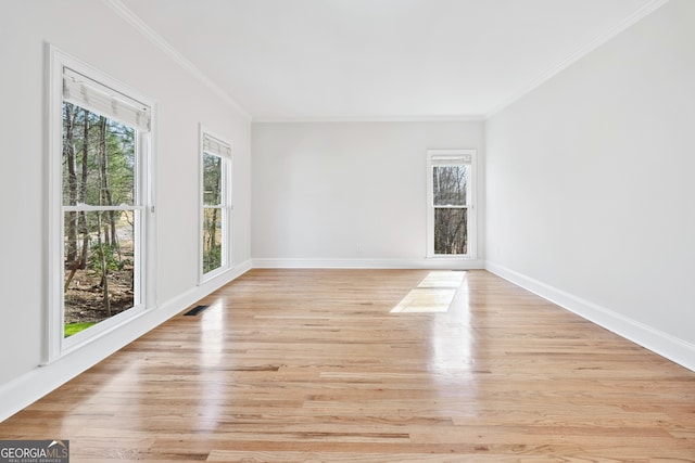 empty room with plenty of natural light, visible vents, and crown molding