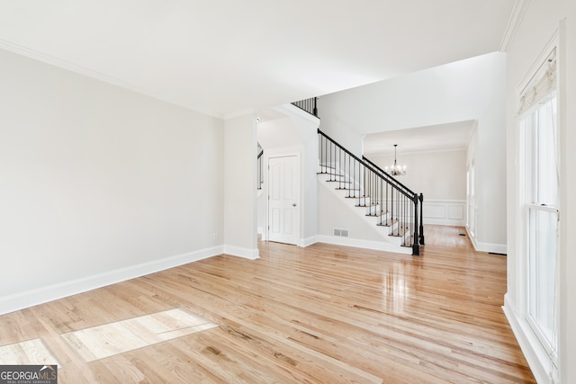 interior space featuring light wood finished floors, an inviting chandelier, visible vents, crown molding, and stairs