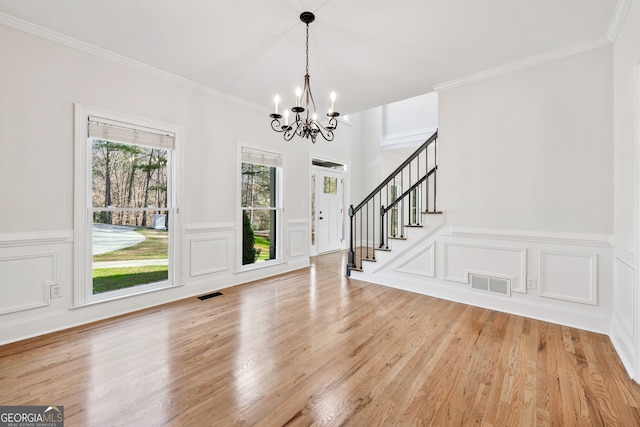 entryway featuring a decorative wall, visible vents, and a notable chandelier