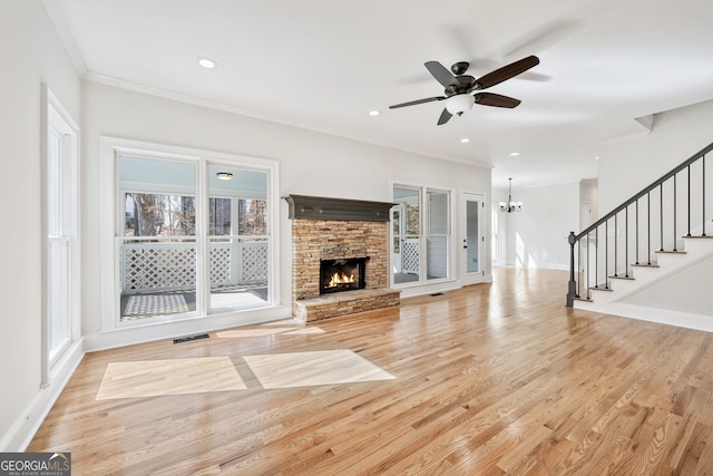 unfurnished living room featuring stairs, ceiling fan with notable chandelier, light wood finished floors, ornamental molding, and visible vents