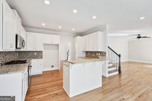 kitchen featuring a peninsula, appliances with stainless steel finishes, light stone counters, and baseboards