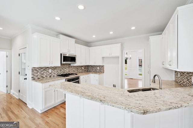 kitchen with a sink, stainless steel microwave, light stone countertops, crown molding, and a peninsula