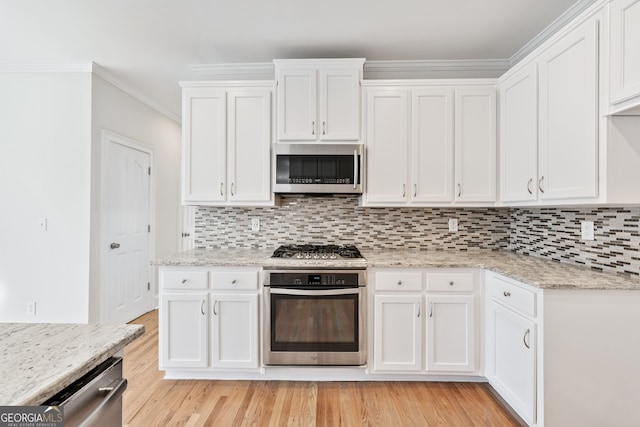 kitchen with backsplash, appliances with stainless steel finishes, light wood-style floors, and white cabinetry