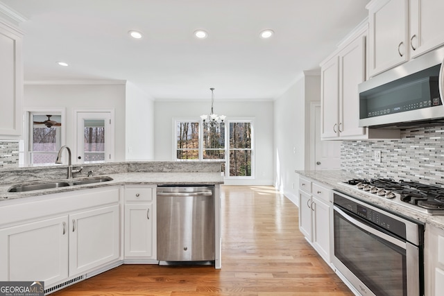 kitchen featuring stainless steel appliances, a sink, ornamental molding, and tasteful backsplash