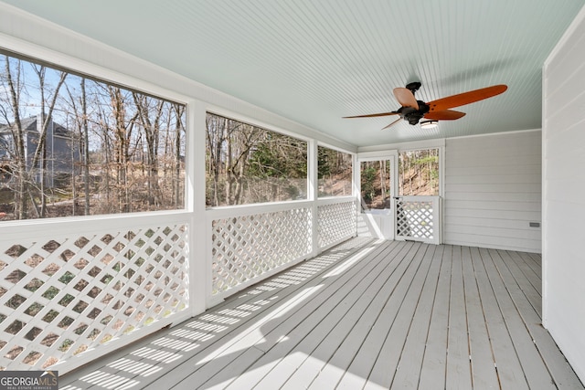 unfurnished sunroom featuring a ceiling fan and plenty of natural light