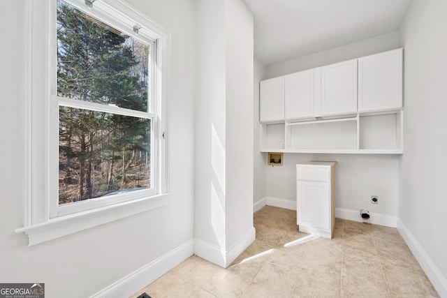 laundry area with electric dryer hookup, hookup for a washing machine, cabinet space, and a healthy amount of sunlight