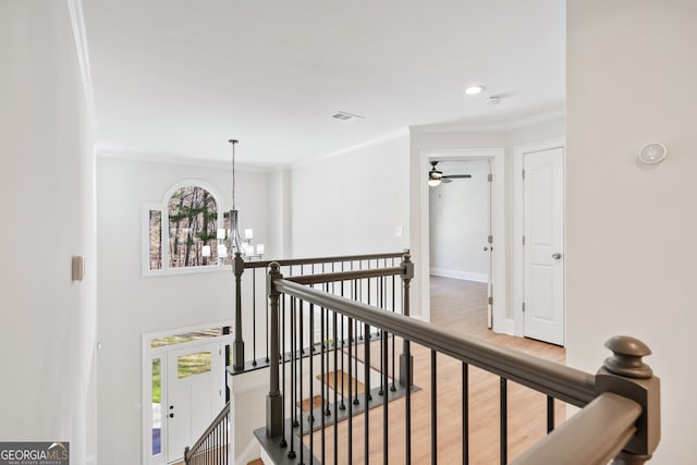 hall featuring baseboards, visible vents, an inviting chandelier, an upstairs landing, and ornamental molding