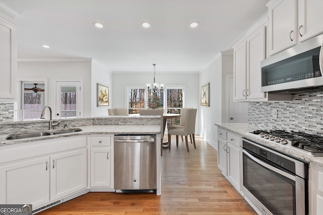 kitchen with a notable chandelier, decorative backsplash, appliances with stainless steel finishes, and a sink