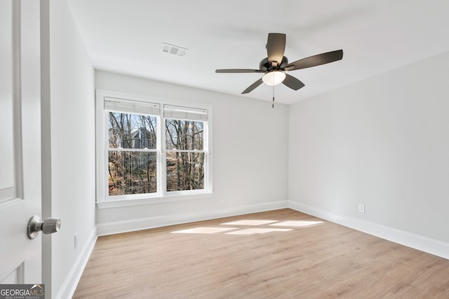 unfurnished room with light wood-type flooring, visible vents, a ceiling fan, and baseboards