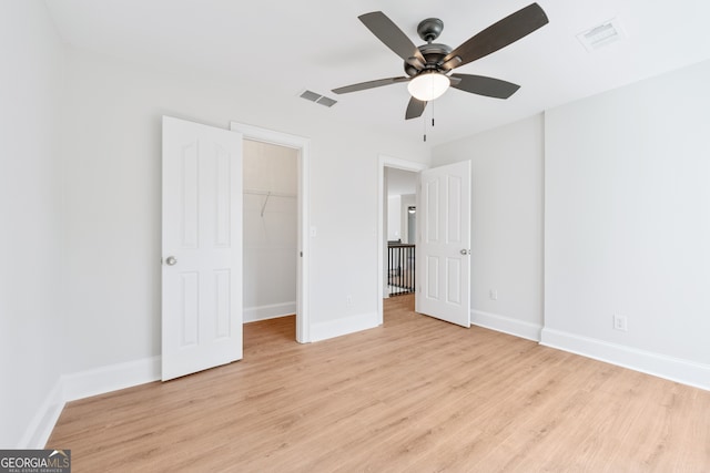 unfurnished bedroom featuring baseboards, visible vents, a spacious closet, and light wood-style floors