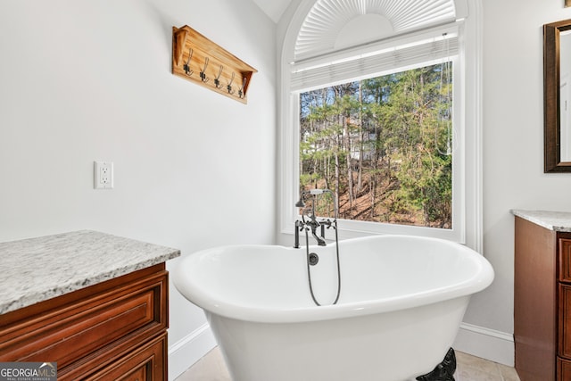 bathroom featuring baseboards, a soaking tub, and vanity