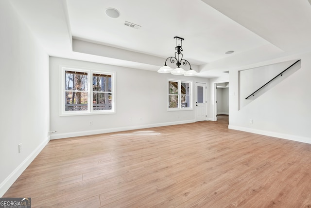unfurnished living room featuring plenty of natural light, light wood-style flooring, visible vents, and baseboards