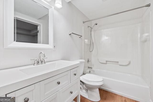 bathroom with wood finished floors, vanity,  shower combination, and toilet