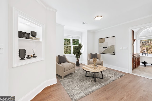 sitting room featuring plenty of natural light, visible vents, baseboards, and wood finished floors