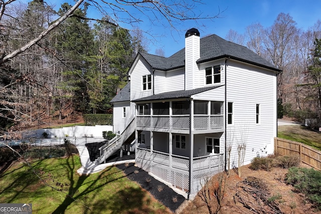 back of house with a chimney, stairs, fence, roof with shingles, and a sunroom