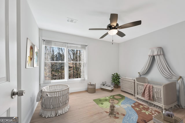 living area featuring baseboards, wood finished floors, visible vents, and a ceiling fan