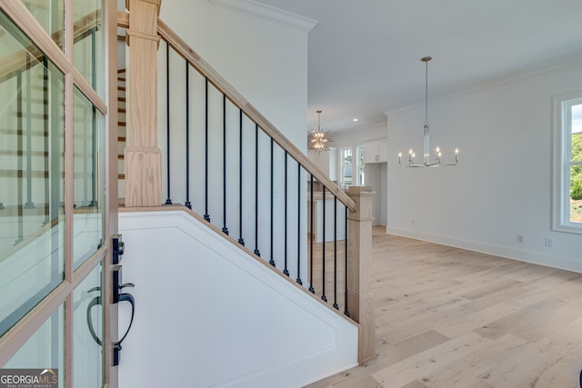 staircase featuring crown molding, wood finished floors, a chandelier, and plenty of natural light