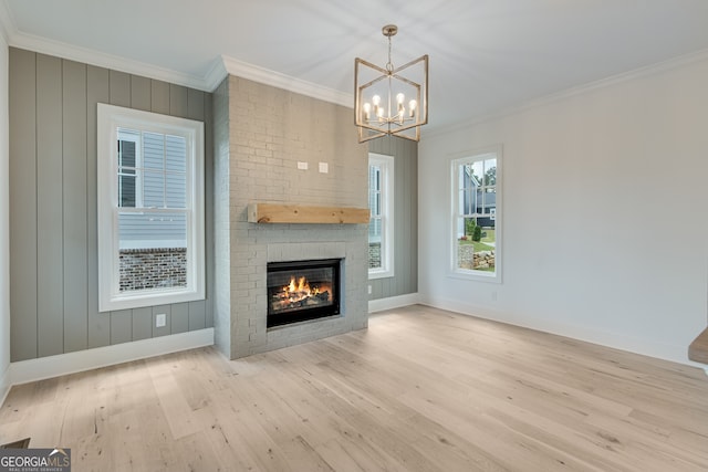 unfurnished living room featuring baseboards, wood finished floors, an inviting chandelier, and crown molding