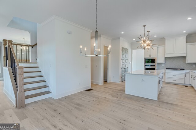 kitchen featuring crown molding, a notable chandelier, stainless steel appliances, and light wood finished floors