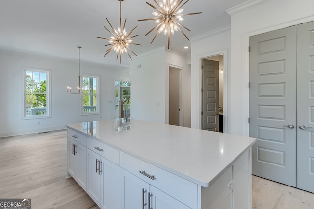 kitchen featuring light wood finished floors, an inviting chandelier, a kitchen island, crown molding, and white cabinetry
