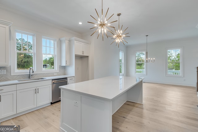 kitchen with a center island, stainless steel dishwasher, a sink, a notable chandelier, and crown molding