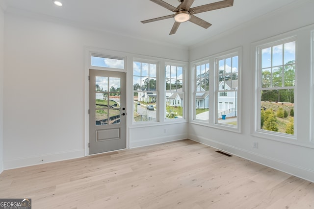 unfurnished sunroom featuring wood finished floors, a wealth of natural light, and crown molding