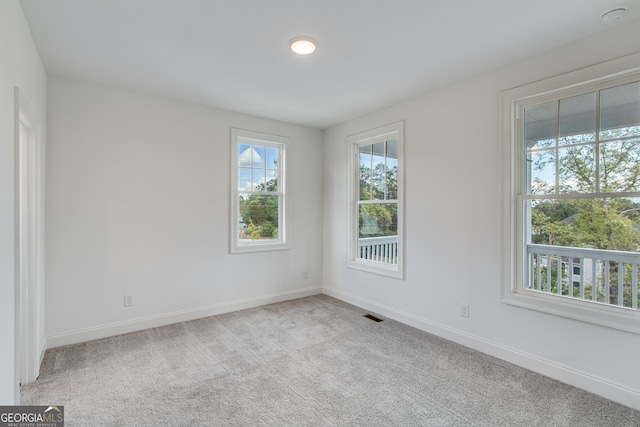 carpeted spare room featuring visible vents and baseboards