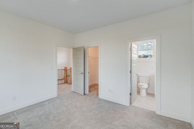 unfurnished bedroom with a closet, a spacious closet, carpet flooring, and baseboards