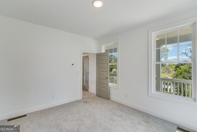 carpeted spare room featuring visible vents and baseboards