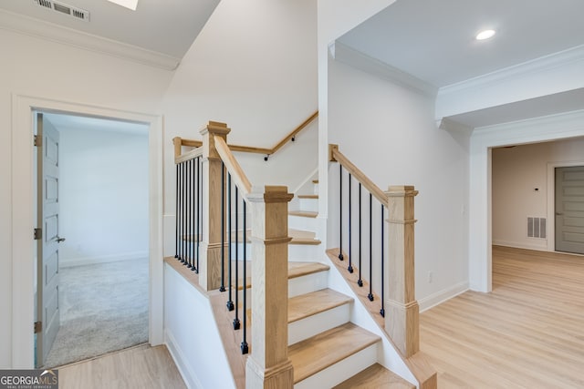 stairway with wood finished floors, visible vents, crown molding, and baseboards