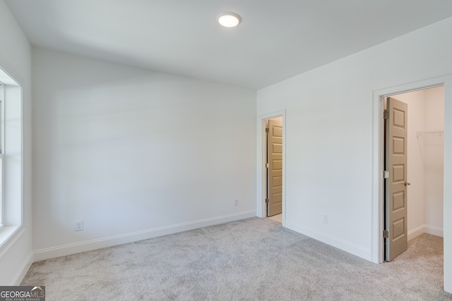 unfurnished bedroom featuring carpet floors, a spacious closet, and baseboards