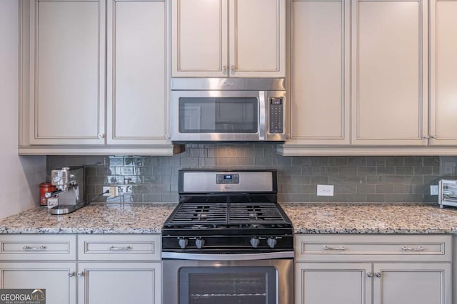 kitchen with stainless steel appliances, decorative backsplash, and light stone countertops