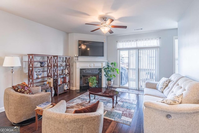 living room with ceiling fan, a fireplace, dark wood-style floors, and baseboards