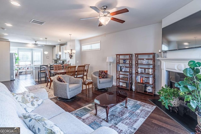 living area with a ceiling fan, a fireplace, wood finished floors, recessed lighting, and a chandelier
