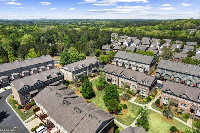 aerial view of property's location featuring a forest and nearby suburban area