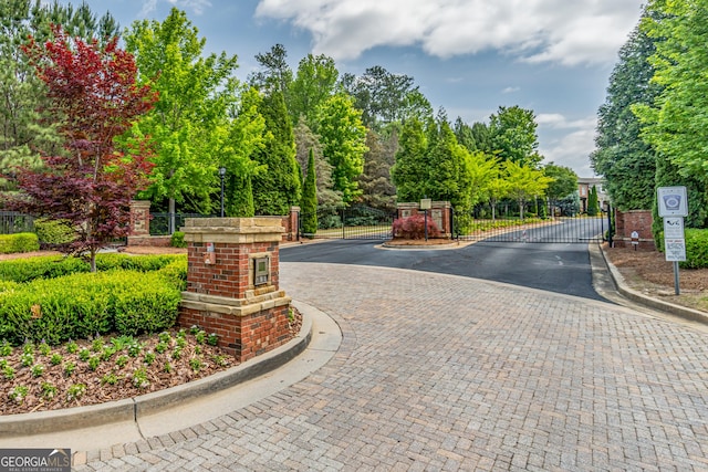 4236 Tacoma Trce, Suwanee, GA 30024 - view of asphalt road featuring a gate, curbs, a gated entry, and view of wooded area