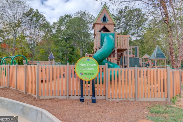 communal playground with fence and view of wooded area
