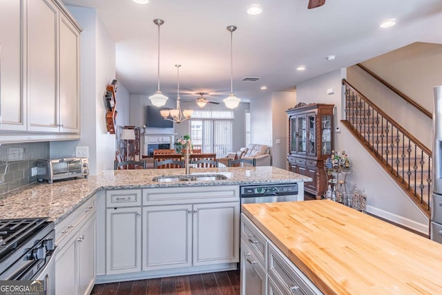 kitchen with a sink, wooden counters, open floor plan, a ceiling fan, and a peninsula