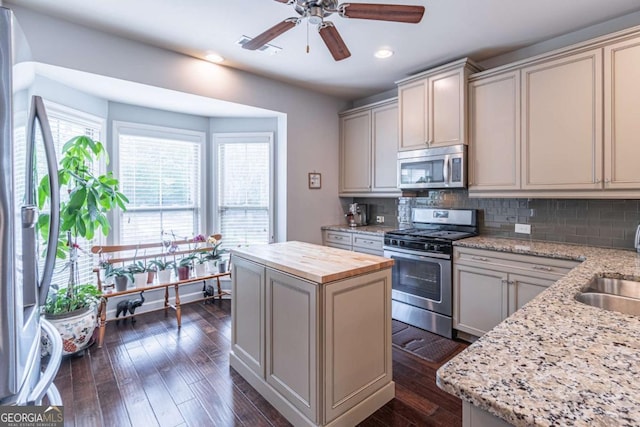 kitchen with stainless steel appliances, plenty of natural light, wood counters, dark wood-type flooring, and recessed lighting