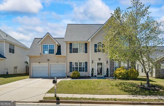 colonial house with an attached garage, a front lawn, and driveway