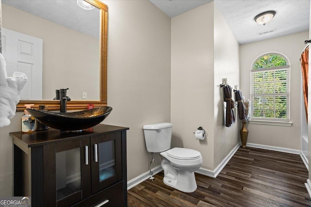 full bath with wood finished floors, visible vents, toilet, vanity, and baseboards