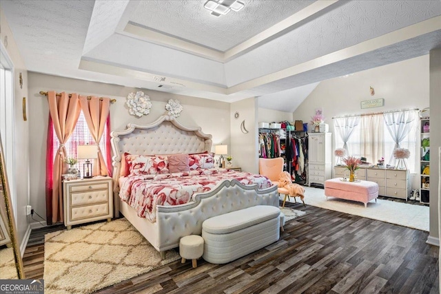 bedroom with a tray ceiling, wood finished floors, and a textured ceiling