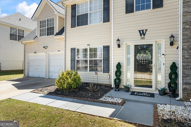 view of exterior entry featuring an attached garage and concrete driveway