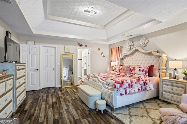 bedroom with visible vents, wood finished floors, a textured ceiling, and a raised ceiling