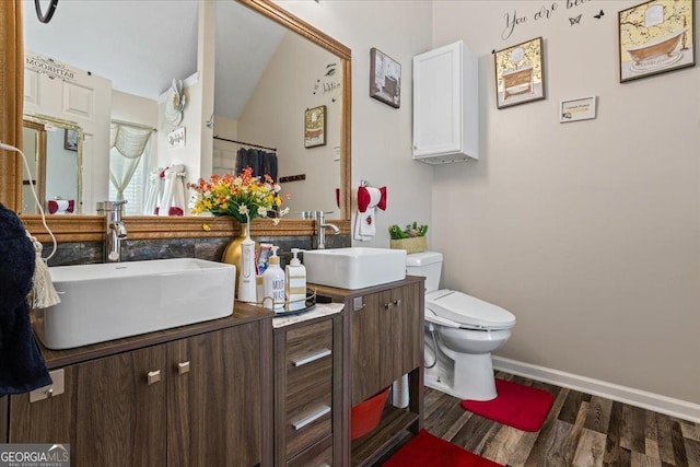 full bath featuring toilet, wood finished floors, a sink, and double vanity