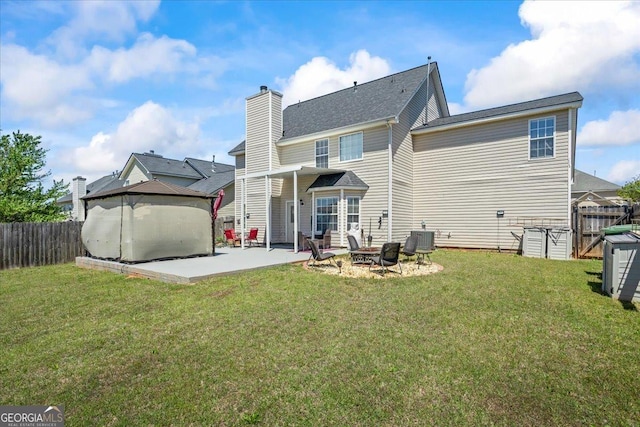 rear view of property featuring a yard, a fenced backyard, a patio, and a chimney