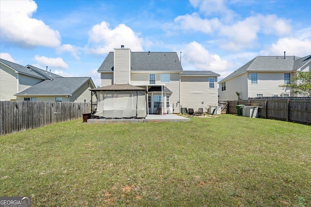 rear view of house featuring a yard, a gazebo, a patio area, and a fenced backyard
