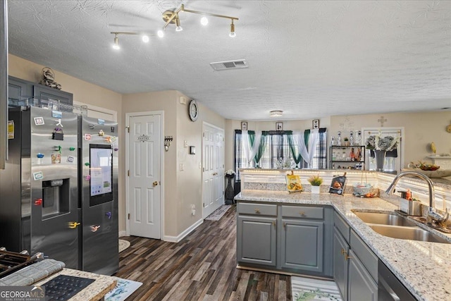 kitchen with a sink, appliances with stainless steel finishes, gray cabinetry, dark wood-type flooring, and visible vents