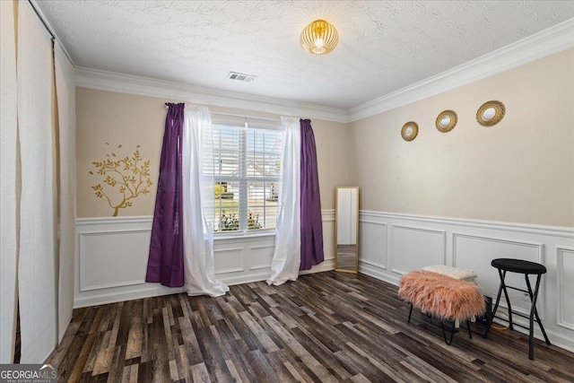 living area with wood finished floors, visible vents, and a wainscoted wall